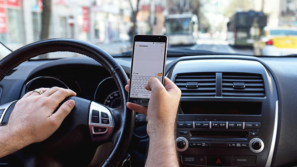 A person distracted while driving using their cell phone.