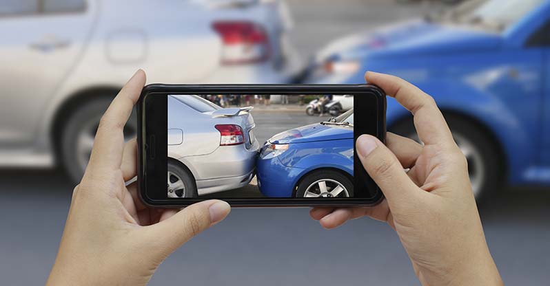 Reporting an auto accident and taking photos with a mobile phone to help document the crash scene.